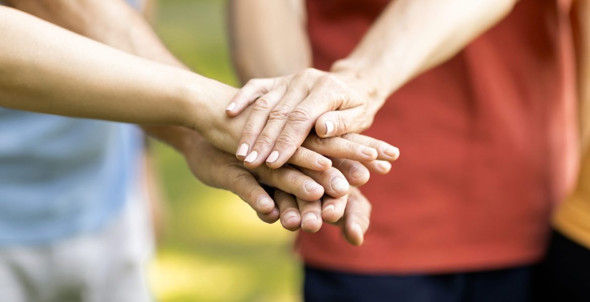 Unity Concept. Group Of Mature People Joining Hands Together While Standing Outdoors