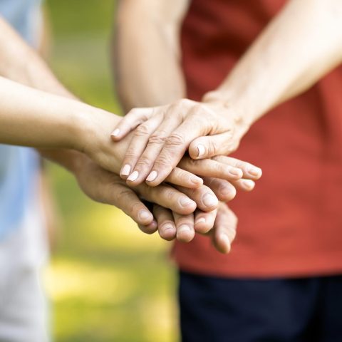 Unity Concept. Group Of Mature People Joining Hands Together While Standing Outdoors