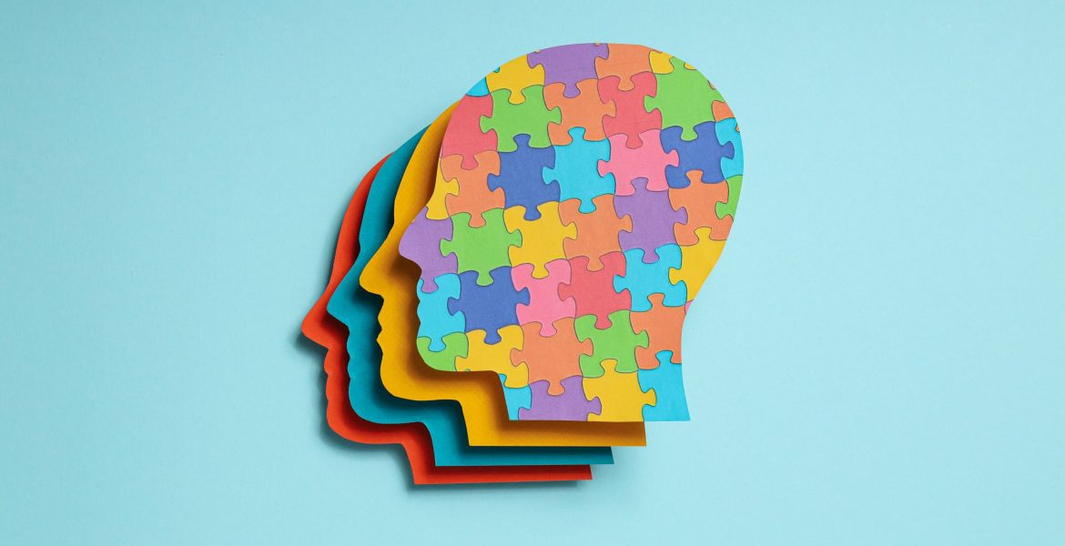 Paper human heads with colorful puzzle pieces on a light backgro