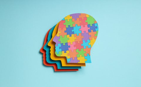 Paper human heads with colorful puzzle pieces on a light backgro