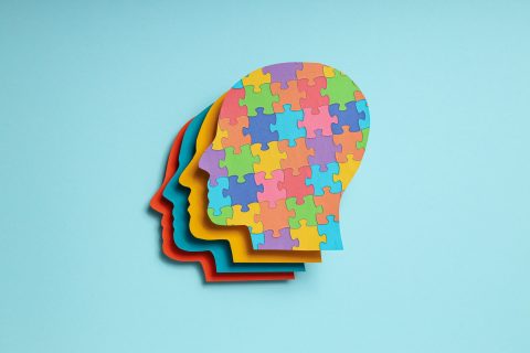 Paper human heads with colorful puzzle pieces on a light backgro
