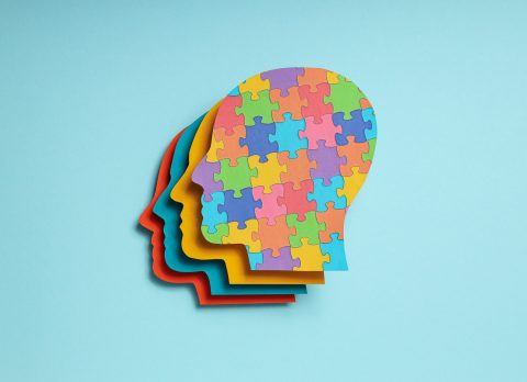 Paper human heads with colorful puzzle pieces on a light backgro