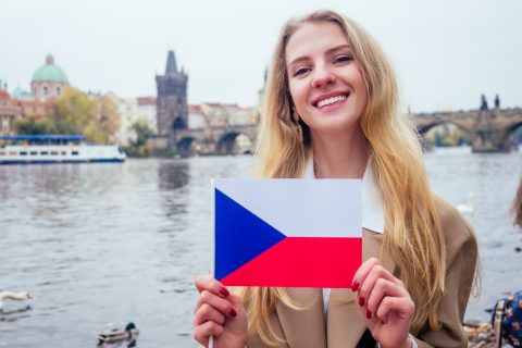 woman with an appetite eats a traditional The Charles Bridge and wawing with flag