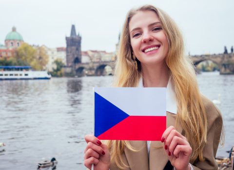 woman with an appetite eats a traditional The Charles Bridge and wawing with flag